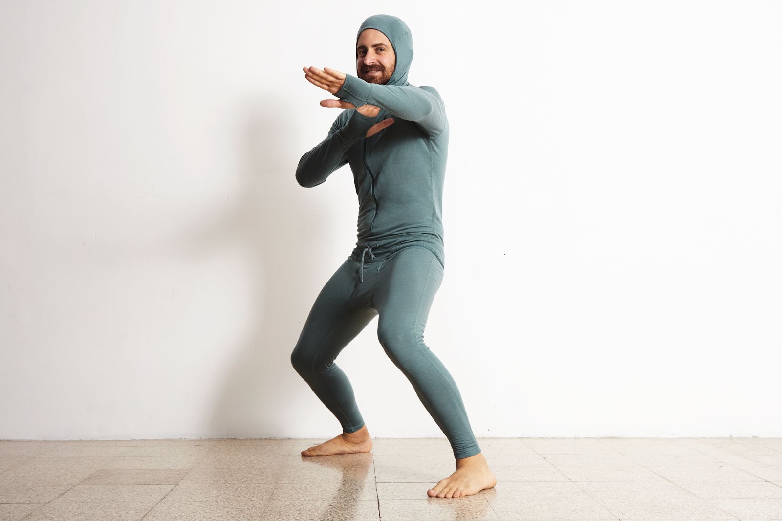 happy-smiling-bearded-fitted-male-wearing-snowboarding-thermal-baselayer-suite-from-merino-wool-and-acts-like-a-ninja-in-defend-position-isolated-on-white.jpg